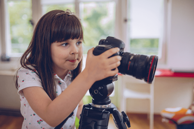 Child looking into a camera on a tripod.