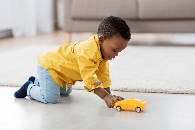 Photo of little boy playing with a toy car to illustrate using higher ISO values to improve clarity.