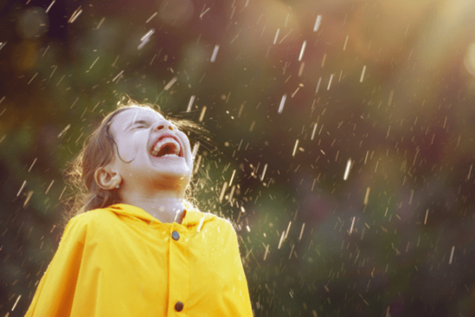 Photo of a child laughing in the rain to illustrate capturing emotion in photos.