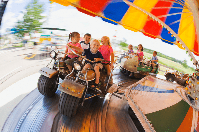 Photo of children riding a carnival ride in the forefront to illustrate panning.