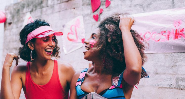 Two women in front of wall with red hearts and signs.