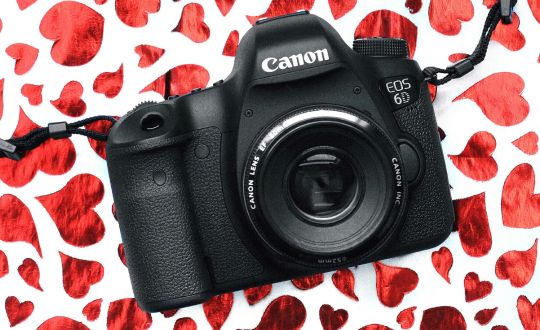 Canon camera on background of red foil hearts.