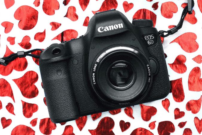 Canon camera on background of red foil hearts.